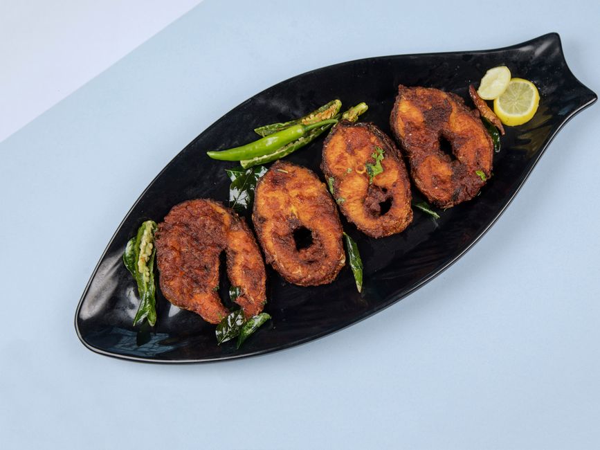crispy white fish fillet with lemon slice and herbs on plate