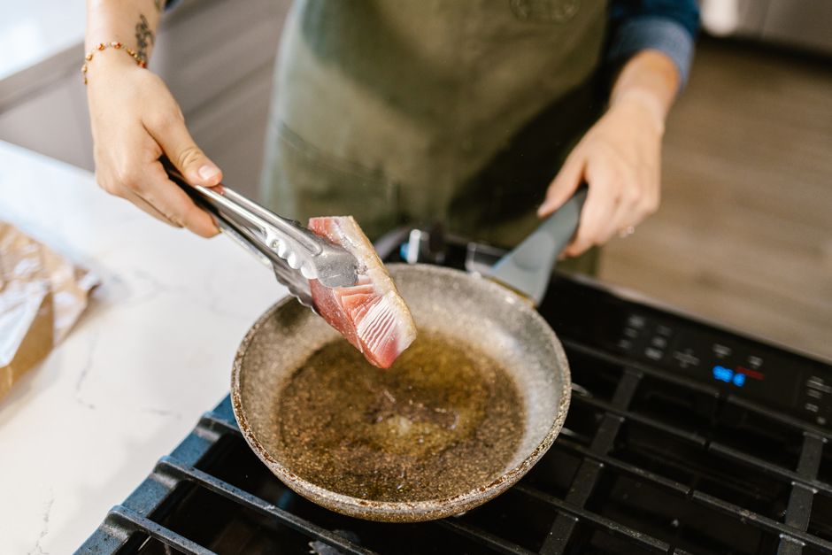 flipping fish fillet with spatula in skillet