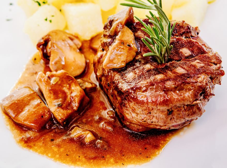 sliced pork tenderloin with mushroom sauce in pan